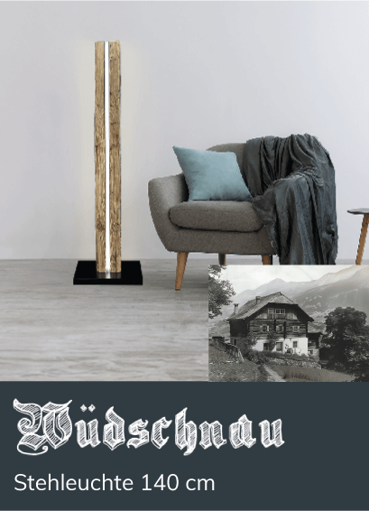 Holz-Stehleuchte mit leuchtendem Streifen steht neben einem grauen Sessel mit Kissen und Decke in einem modernen Wohnzimmer. Text: &bdquo;W&uuml;dschnau Stehleuchte 140 cm&ldquo;. Schwarzwei&szlig;foto eines Chalet.